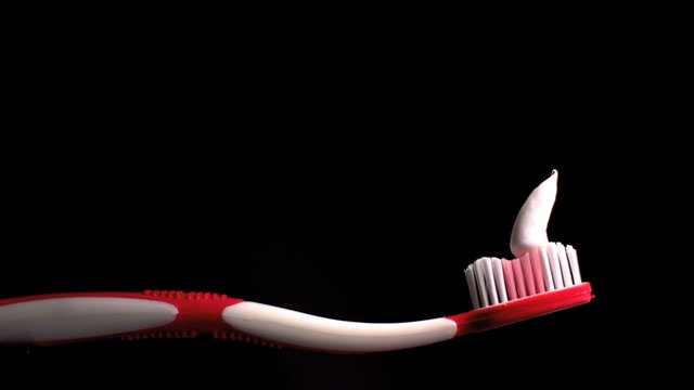Toothpaste falling on pink toothbrush