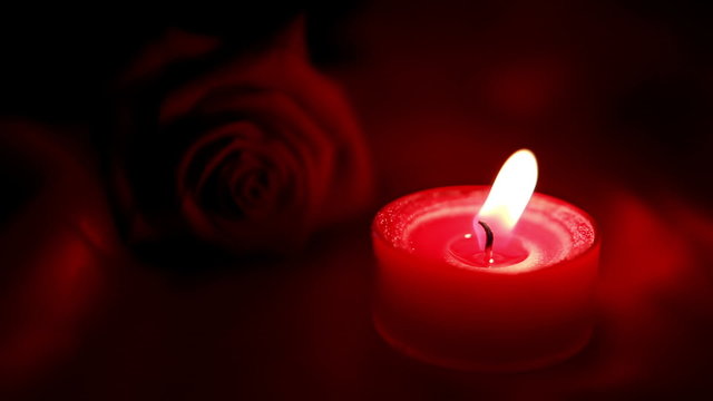 Candle flickering beside red roses and going out