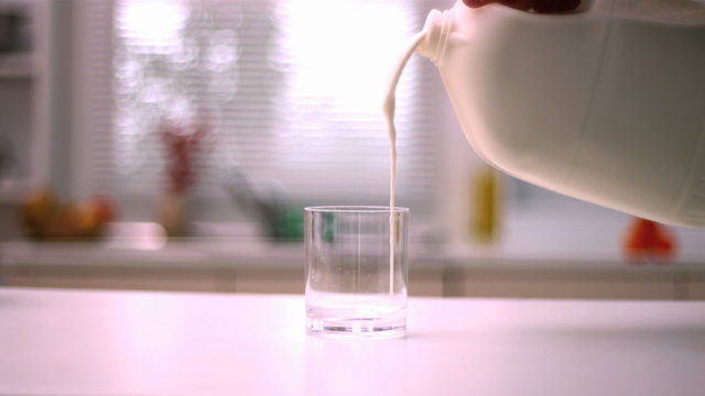 Milk pouring into small glass in kitchen