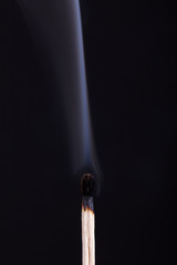 extinguished match with smoke on black background