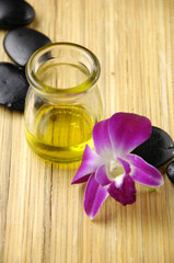 Pink orchid with stone and bottle of aromatherapy oil