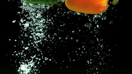Yellow and green peppers falling in water in slow motion - Powered by Adobe