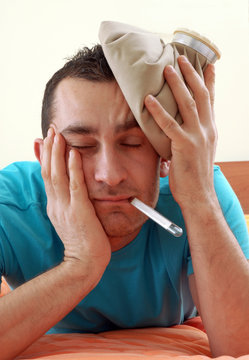 Hombre con dolor de cabeza sujetando una bolsa fr&iacute;a.