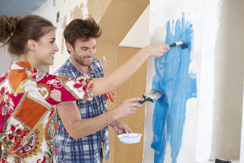 Wall mural young couple painting wall to blue