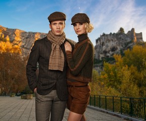 Elegant couple in caps against autumnal landscape