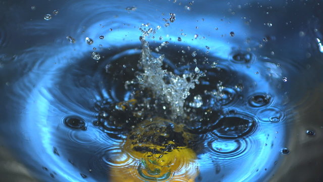 Yellow capsicum falling into water in slow motion