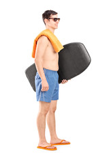 Full length portrait of a male surfer holding a surfboard