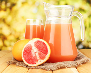 Full glass and jug of grapefruit juice and grapefruits