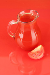 Full jug of tomato juice, on color background