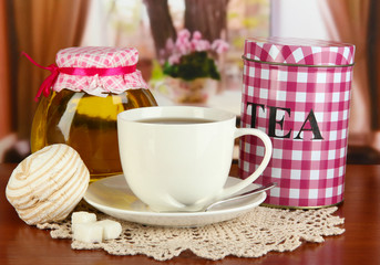Jar and cup of tea on table in room