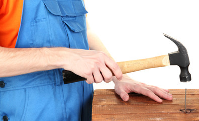Builder hammering nails into board isolated on white