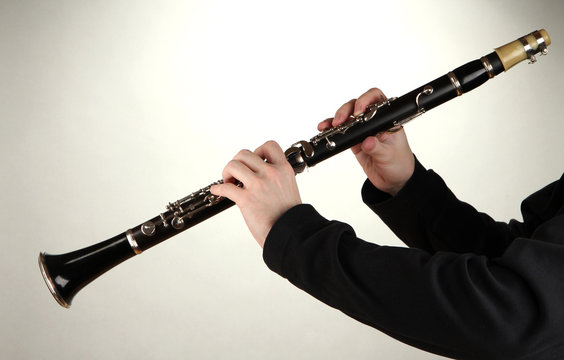 Musician playing on clarinet on grey background
