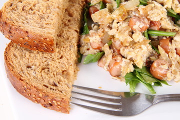Scrambled eggs with frankfurters and spinach, and a fork
