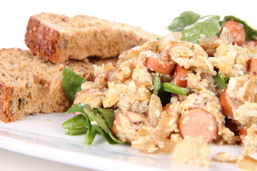 Scrambled eggs with frankfurters and spinach, and a fork