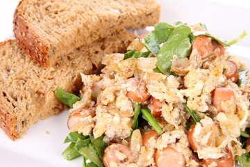 Scrambled eggs with frankfurters and spinach, and a fork