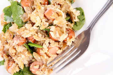 Scrambled eggs with frankfurters and spinach, and a fork