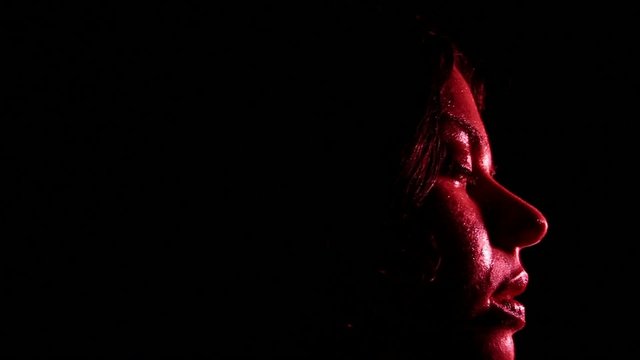 volto di ragazza che dorme e sogna nell'oscurit&agrave; con luce rossa