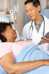 Doctor Using Digital Tablet Talking With Senior Patient