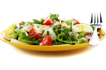 Salad with tomatoes, cheese and chicken in a yellow plate.