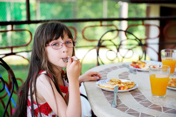 Little girl having breakfast outdoors
