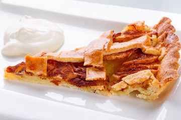 Piece of apple tart and cream on the plate
