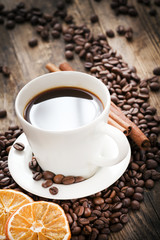 Cup of coffee and coffee beans, warm lighting.