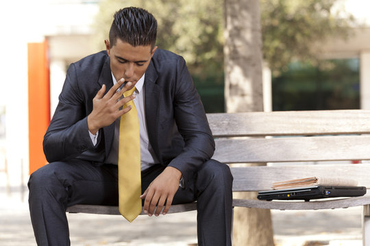 Frustrated businessman smoking a cigar to relax
