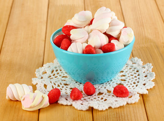 Gentle marshmallow in glass vase on wooden table close-up