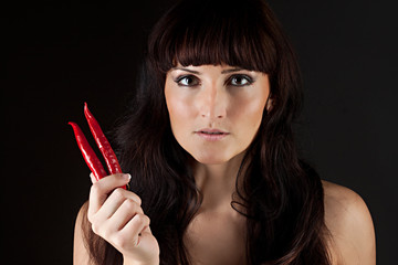 Obraz premium beautiful woman looking hot spicy chili pepper
