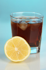 Glass of whiskey with ice and lemon on blue background
