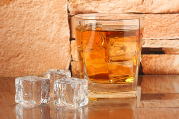 Glass of whiskey and ice on brick wall background