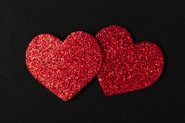 Red shiny hearts on black background