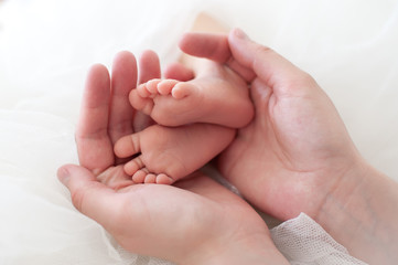 Women's hands holding baby feet.