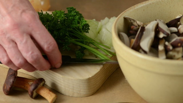 Putting a bunch of parsley herb on board with knife and onion