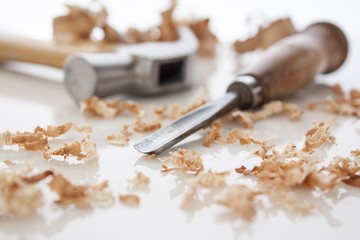 hammer and chisel on a white board with sawdust shavings