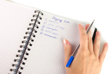 woman's hand holding a notebook with a shopping list close-up