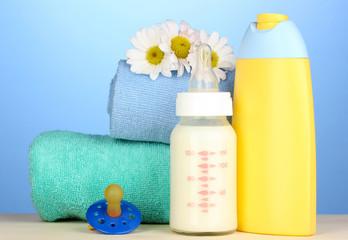 Fototapeta na wymiar Butelek z mlekiem i szampon najbliższą ręczniki na niebieskim tle
