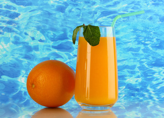 Glass of orange juice with mint and orange on sea background