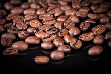 Fresh roasted coffee beans on black shine table. Closeup photo