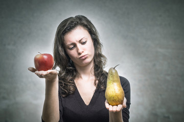 Junge Frau vergleicht Apfel und Birne