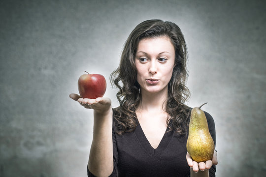 Junge Frau vergleicht Apfel und Birne