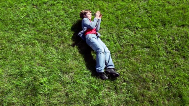 Little boy rolls by green grass plot