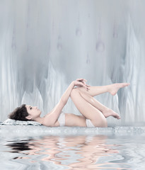 A woman laying in lingerie on a light grey abstrack background