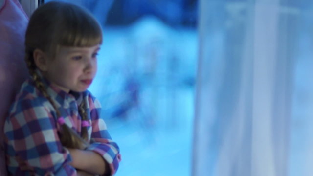 Sad child looking in window at snow-covered playground
