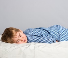 Little boy in blue pyjamas sleeping in bed