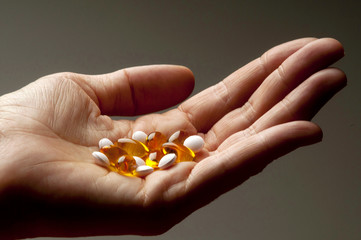 Closeup of  hand holding vitamin E and vitamin D capsules