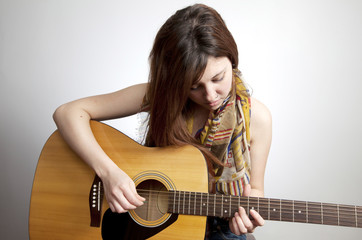 Young teenaged girl with nose ring playing acoustic guitar