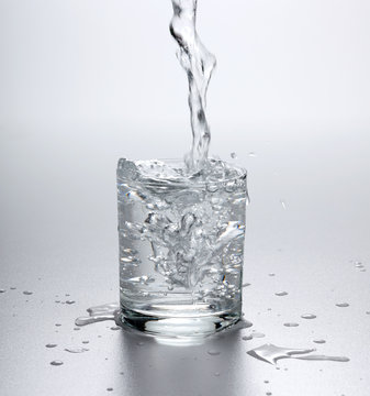 Water flowing into full glass