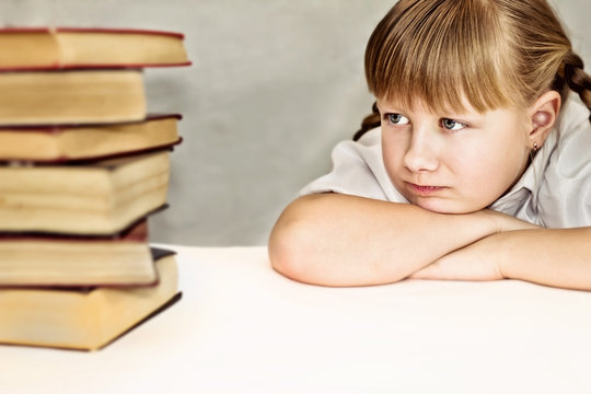 Little girl discontentedly looking at  books