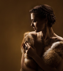 Woman in luxury fur coat. Vintage style. Brown background.